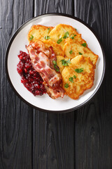 Swedish food potato pancakes with lingonberry jam and bacon close-up in a plate on the table. vertical top view from above