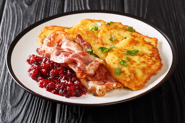 Raggmunk or rarakor is one of the most swedish dishes it pancakes mixed with shredded potatoes serve side pork with lingonberry jam close-up in a plate on the table. horizontal