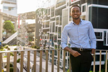Portrait of handsome black African businessman outdoors in city during summer