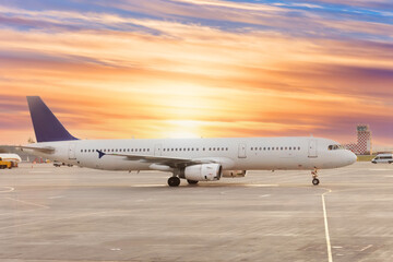 Fototapeta na wymiar Passenger airplane on runway near the terminal in an airport at sunset time.