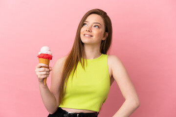 Teenager girl with a cornet ice cream over isolated pink background thinking an idea while looking up