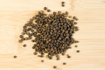 Pile of Black peppercorns Black pepper dried seeds on bamboo wooden background