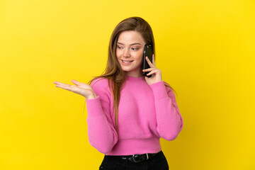 Teenager girl using mobile phone over isolated yellow background extending hands to the side for inviting to come