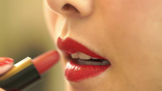 close up shot. Young woman uses red lipstick to paint her lips bright and beautiful. It's the makeup routine every morning. Before going out or going to work.