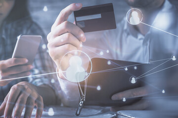 Double exposure of man and woman on-line shopping holding a credit card and social network theme hologram drawing. People connecting and E-commerce pay on-line concept.