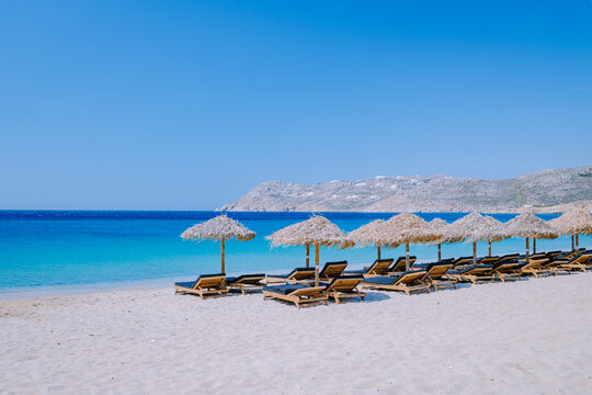 Elia Beach Mykonos, a young guy on the beach of Mykonos during summer with an umbrella and luxury beach chairs beds, the blue ocean at Elia beach Mykonos Greece. 