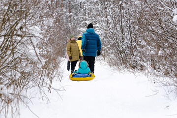 A married couple with children and friends go for a walk in the winter snow-covered forest. People, lifestyle concept