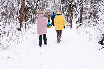A married couple with children and friends go for a walk in the winter snow-covered forest. People, lifestyle concept