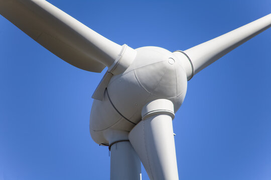 Detailed close up view of a wind turbines; generator, rotor and blade view on blue sky background