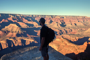 Hiker man with backpack watching breathtaking views of the Grand Canyon, Arizona, USA
