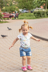 Little girl toddler runs after pigeons. Summertime