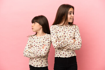 Little sisters girls isolated on pink background with confuse face expression while bites lip