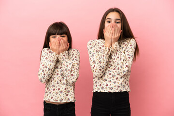 Little sisters girls isolated on pink background smiling a lot while covering mouth