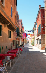 tables and chairs of an alfresco bar on the island of Venice without people