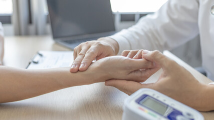 Medical professional measures the pulse of a male patient's wrist to check his heart rate in the hospital's examination room, Doctor checking patient health, Initial symptom check.