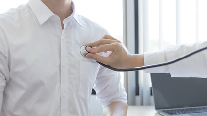Male doctor uses a stethoscope to measure the patient's heart to check for any abnormalities in his...