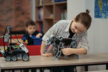 Two kids of different age choose parts of robotic electric toys for building robots at robotics...