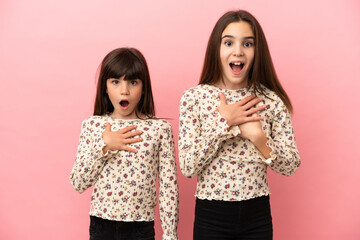 Little sisters girls isolated on pink background surprised and shocked while looking right
