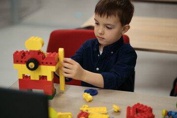 One kid choose parts of robotic electric toys for his age of four to build robots at robotics...