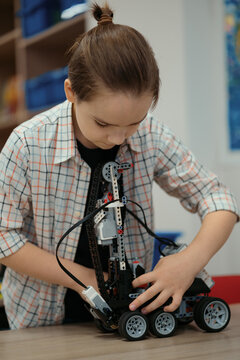 Boy Works on a Fully Functional Programable Robot for His School Robotics Club Project.