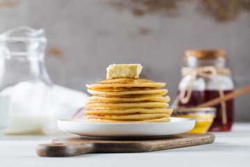 The pancakes are stacked in a plate with a piece of butter and drizzled with honey sauce. Breakfast concept.