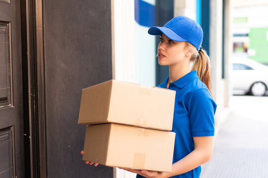 Young delivery woman at outdoors holding boxes