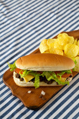 Homemade Chopped Beef Sandwich with Potato Chips on a rustic wooden board, low angle view.