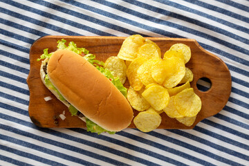 Homemade Chopped Beef Sandwich with Potato Chips on a rustic wooden board, top view. Flat lay, overhead, from above.