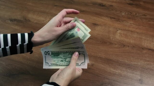 Hands hold dollar bills as fan shape and inspecting to found damaged banknotes marked and old unfit bill, separate unfit paper currency and counting dollars on wooden background with copy space