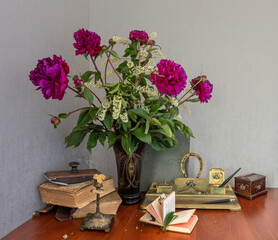 Still life with a bouquet of white bird cherry with red peonies and books. Vintage.