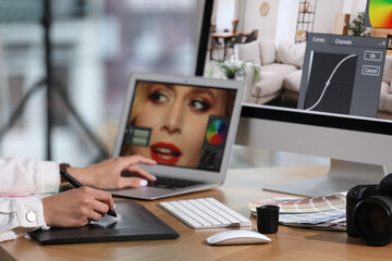 Professional retoucher working on graphic tablet and laptop at table, closeup