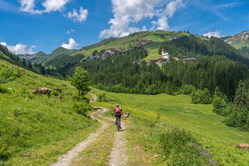 happy senior woman riding her electric mountain bike up to thr famous mountain village of Damuels in the Bregenz Forest mountain of Vorarlberg, Austria