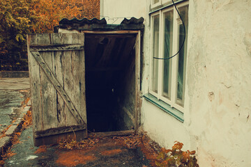Old cellar entrance with wooden door on a rainy day near an asylum, horror concept