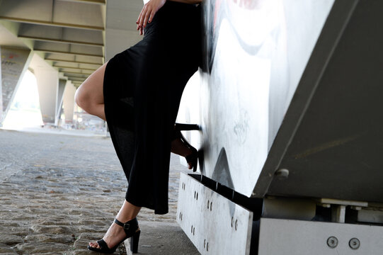 Frau steht outdoor in geschlitzten rock und zeigt rasierte beine wartend 