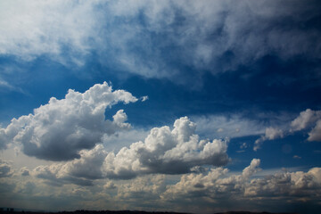 Naklejka na ściany i meble Blue sky and cottony clouds on a partly cloudy and bright day. Cumulus clouds. copy space.