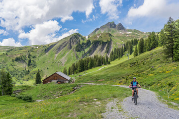 happy senior woman riding her electric mountain below Mittagsspitze summit near the  village of...
