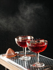 Two refreshing cocktails being sprinkled on a black background