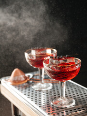 Two refreshing cocktails being sprinkled on a black background