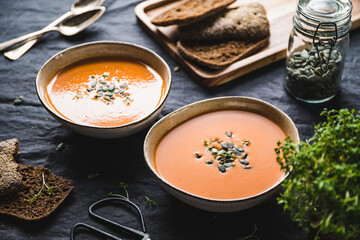 Vegetable creamy healthy soup with pumpkin seeds on a kitchen table.