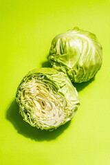 Obraz premium Fresh young cabbage, half and whole on bright green background