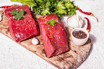 Raw beef steaks on a wooden cutting board