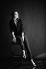 Beautiful woman sits on a chair and looks at you