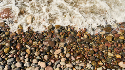 Wellen spülen Wasser über Steine und Kiesel am Strand