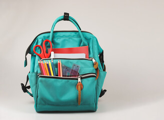 Front view  of backpack with school supplies on white  background with copy space.