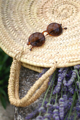 Straw bag filled with fresh lavender flowers and retro sunglasses. Selective focus.