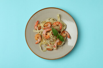 Plate of tasty shrimp pasta on blue background