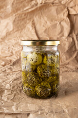 Closeup of glass jar full of herbal mozzarella cheese, paper background