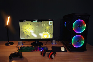 Modern computer and RGB keyboard on wooden table in room