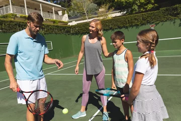 Foto op Canvas Happy caucasian couple with daughter and son outdoors, playing tennis on tennis court © WavebreakMediaMicro
