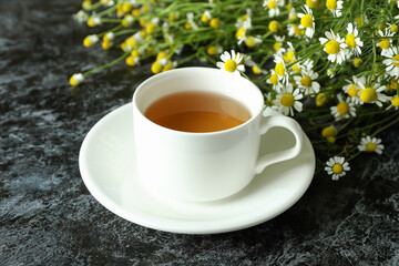 Cup of chamomile tea on black smokey table